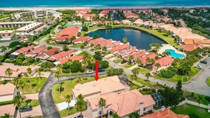 Un quartier résidentiel en bord de mer, doté d’une grande piscine, de nombreuses maisons aux toits rouges et offrant une vue sur l’océan.