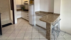 A modern kitchen with white cabinets, a granite countertop, and a stainless steel refrigerator.
