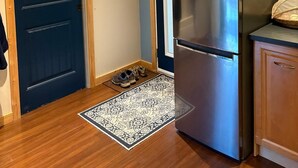 A compact kitchen with a stainless steel refrigerator, a blue door, and a patterned rug.