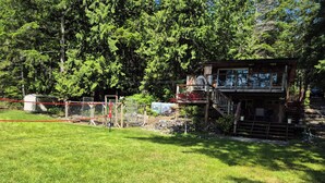 A two-story wooden cabin with a deck and a fenced area.