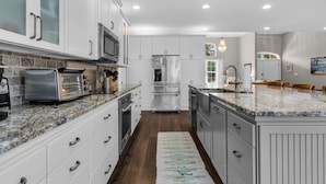 A modern kitchen with white cabinetry, stainless steel appliances, and a large island with a granite countertop. - Seacrest 4BR w/ Private Heated Pool + Beach Access & Dolphin Cruise Ticket! (Panama City Beach)