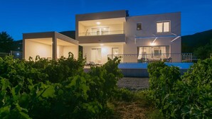 A modern two-story house with a balcony and a pool, surrounded by lush greenery. - Villa Vista Vinea – Private heated pool villa close to Split and Trogir (Kaštel Novi)