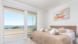 A bedroom with a large bed, a view of the sea, and a painting on the wall. - Villa Vista Vinea – Private heated pool villa close to Split and Trogir (Kaštel Novi)