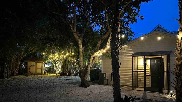A house with a covered porch, a small shed, and string lights. - Naples Serene Studio (Naples)