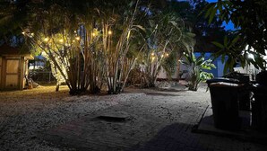 A nighttime outdoor area with a pathway, palm trees, and string lights. - Naples Serene Studio (Naples)