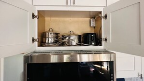 A kitchen with a built-in microwave, a stove, and pots and pans stored in a cabinet. - Naples Serene Studio (Naples)