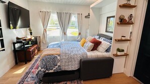 A modern bedroom with a large bed, a TV mounted on the wall, and a desk with a computer. - Naples Serene Studio (Naples)