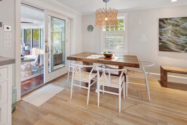 Une cuisine moderne avec une table à manger en bois, des chaises blanches et un luminaire suspendu.
