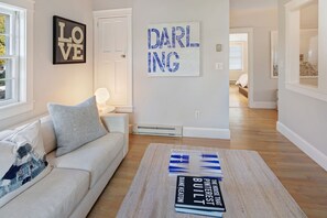 Ein modernes Wohnzimmer mit einer Couch, einem Teppich und Büchern auf einem Couchtisch.