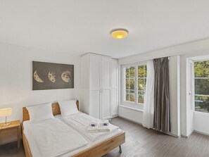 A bedroom with a bed, a nightstand, a wardrobe, and a window with curtains. - Charming Studio in the old town - UZ15 (Zürich)