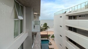 Un edificio moderno con piscina, vistas a la playa y un balcón con barandilla.
