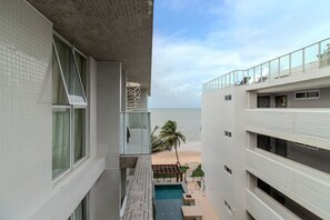 Un edificio moderno con piscina, vistas a la playa y un balcón con barandilla.