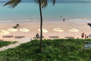 Una playa con sombrillas y gente.