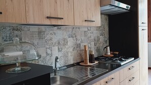 A modern kitchen with wooden cabinets, a stainless steel sink, and a black countertop.