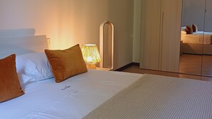 A hotel room with a large bed, a bedside table with a lamp, and a wardrobe.