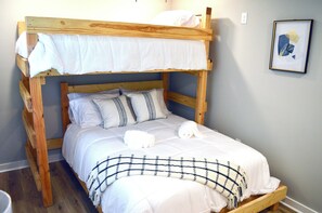 Una cama litera con ropa de cama blanca y una manta a cuadros.