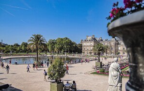 A large open square with a fountain, palm trees, and a statue. - Charming typical studio, Montparnasse  (Paris)