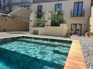Una piscina con agua cristalina, rodeada por un borde de guijarros y una terraza de madera.