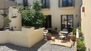 A courtyard with a seating area, potted plants, and a small fountain. - HOTEL SES TERRISSES (Palafrugell)
