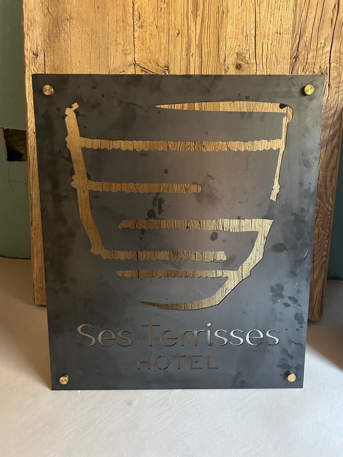Señal para el Hotel Ses Terrisses con un diseño estilizado de un edificio y el nombre del hotel.
