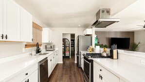 Eine moderne Küche mit weißen Schränken, einem Edelstahl-Kühlschrank, einer Mikrowelle und einem Gasherd.