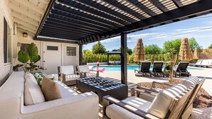 Eine Außenpatio mit Pool, Liegestühlen und einer Feuerstelle.