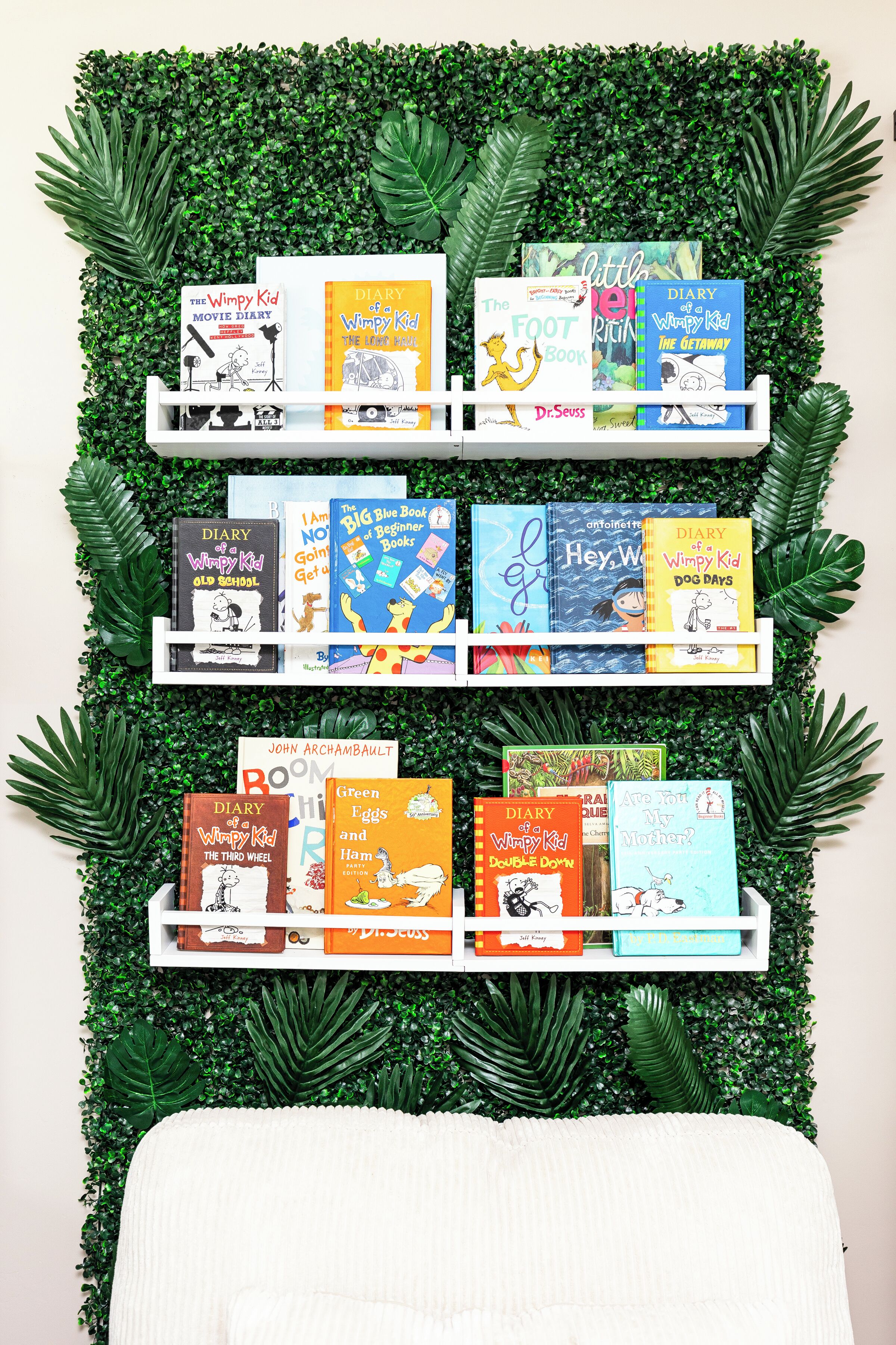Una libreria multistrato con molti libri sullo sfondo di un verde fogliame.