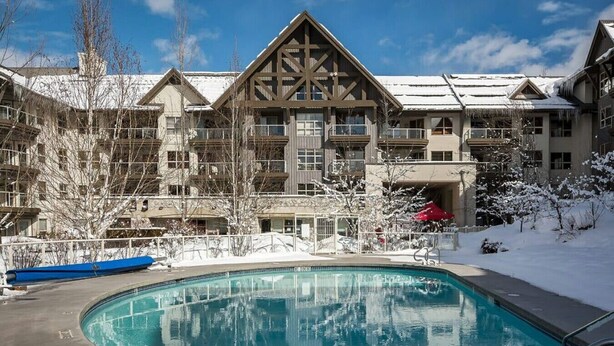 A resort with a pool, multiple buildings, and snowy surroundings.