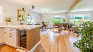 A spacious kitchen with a large island, wooden cabinets, and a dining area with a piano. - 1812 House, 2 Stays, 1 home (Manchester)