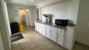 A compact kitchen with a microwave, coffee maker, and a washing machine in the background. - Studio 6 Suites Euless, Tx – Dfw West (Euless)