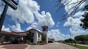 A hotel with a red-tiled roof, a central tower, and a parking lot. - Studio 6 Suites Euless, Tx – Dfw West (Euless)