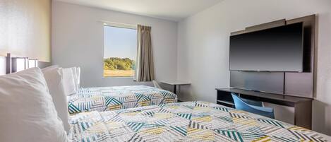 Ett hotellrum med två sängar, en TV, ett skrivbord och ett fönster med utsikt.