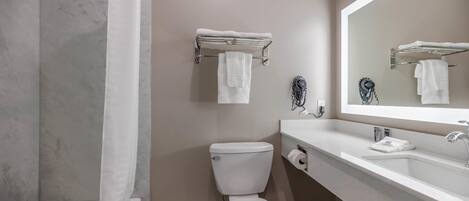 Et badeværelse med toilet, vask, spejl og et håndklædestativ.