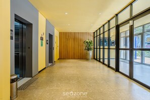 A modern hallway with a wooden panel wall, a trash bin, and a potted plant.