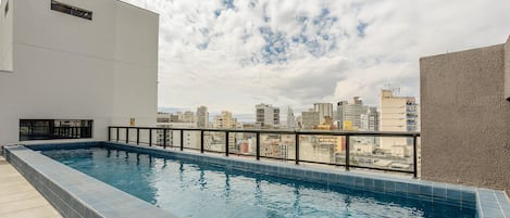 A rooftop swimming pool with a city view, surrounded by buildings.