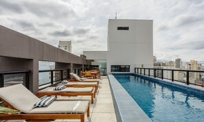 Un espace piscine sur le toit, avec des chaises longues et une piscine.