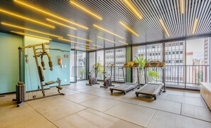 Een sportschool met trainingsapparatuur, grote ramen en een modern plafondontwerp.
