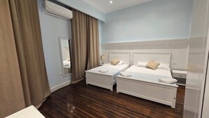 Ett hotellrum med två sängar, en stor spegel, en luftkonditioneringsanläggning och ett trägolv.
