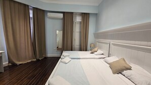 Une chambre d’hôtel avec deux lits, un plancher en bois, un grand miroir et un appareil de climatisation.