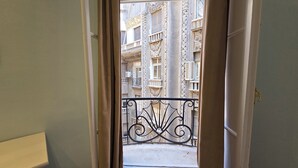 Une vue depuis un balcon orné de balustrades en métal ouvragé, donnant sur un immeuble doté de nombreux balcons et de détails architecturaux.