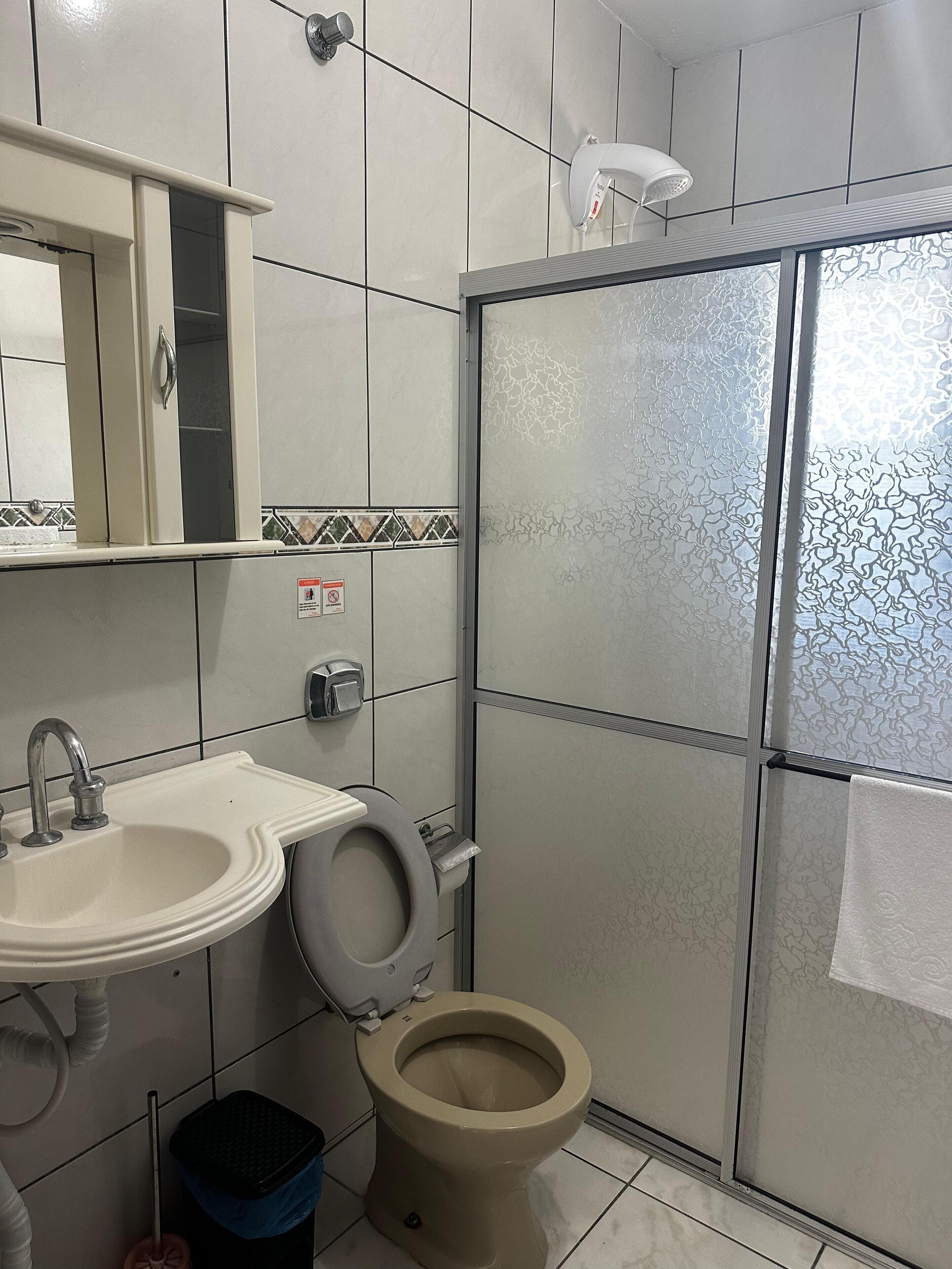 A bathroom with a toilet, sink, and shower.