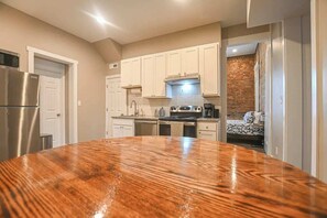 A kitchen with white cabinets, a stainless steel refrigerator, and a wooden dining table. - NULU/Butchertown Key Club and Salon/Spa (Louisville)