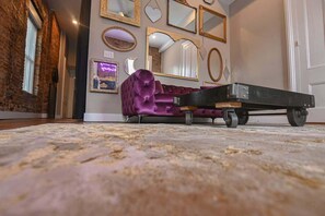 A room with a purple sofa, a cart, and various wall-mounted mirrors. - NULU/Butchertown Key Club and Salon/Spa (Louisville)