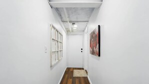 A narrow hallway with wooden flooring, white walls, and a door at the end. - Modern Studio W/Parking/Long-Term Ready (Cincinnati)
