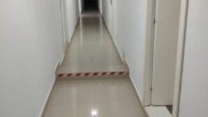 A narrow, well-lit hallway with white walls and a tiled floor, leading to a dark doorway at the end. - Puzzle Magic (Pitești)