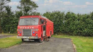 A red Dennis truck parked on a gravel path with a hedge in the background. - Dashing Dennis - 22 (Launceston)