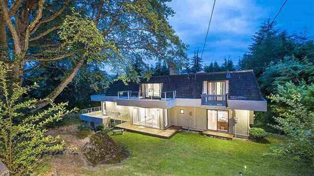 Een modern huis met twee verdiepingen, een balkon, grote ramen en een verzorgd gazon.