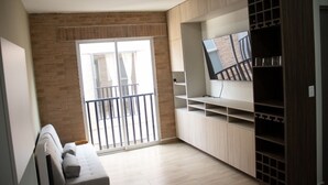A modern living room with a grey sofa, a TV on a wooden stand, and a balcony with a metal railing. - Marvelous 2b2b Pet friendly apartment in Oaxaca “El rincon de Monde Alban” (Oaxaca)