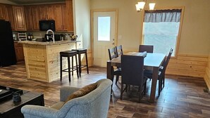 Amplia sala de estar con una mesa y sillas de comedor, un sofá y una cocina con armarios de madera y un microondas.