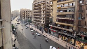 Un hôtel à plusieurs étages doté de balcons, donnant sur la rue, et abritant divers commerces.
